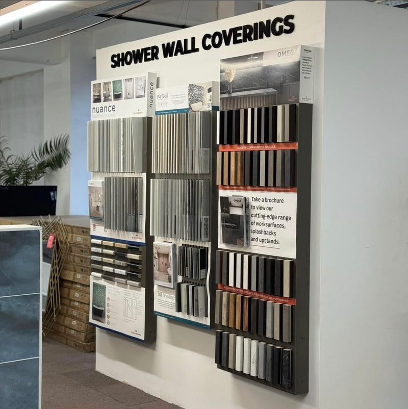 Display of shower wall coverings with various color samples on a wall.