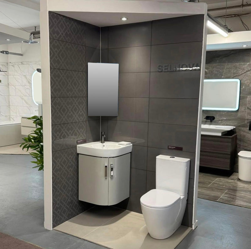 Bathroom setup with toilet, sink, and mirror in a showroom setting.