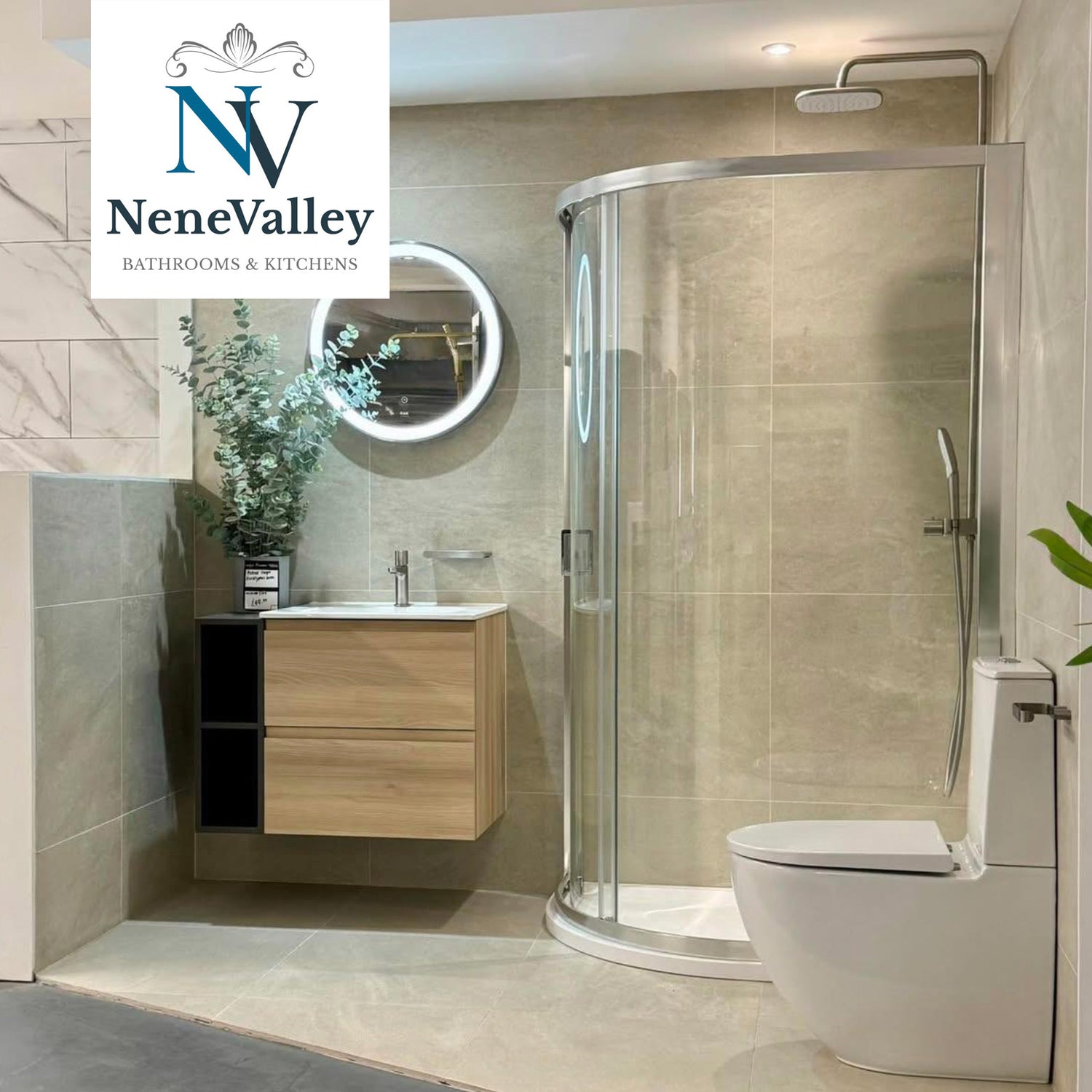 NeneValley Bathroom with glass curved shower enclosure, light wood vanity unit and porcelain toilet. 