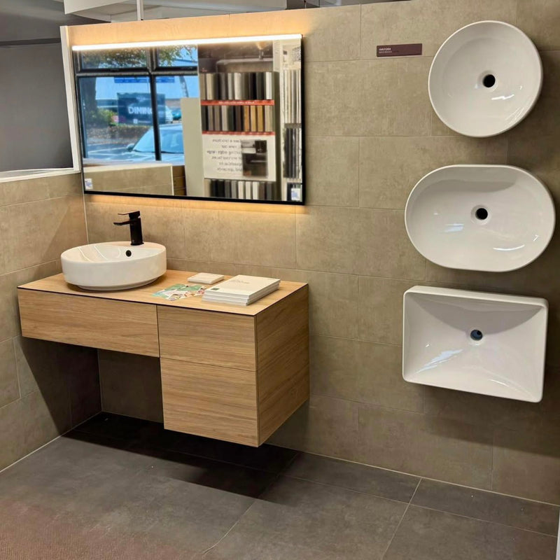 Bathroom setup with a wooden vanity, mirror, and three wall-mounted white basins.
