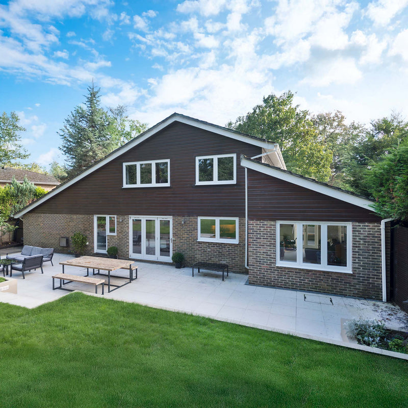 Large Pitched roof house with white window frames and patio doors.